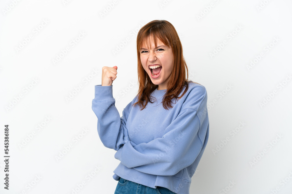 Redhead girl isolated on white background celebrating a victory