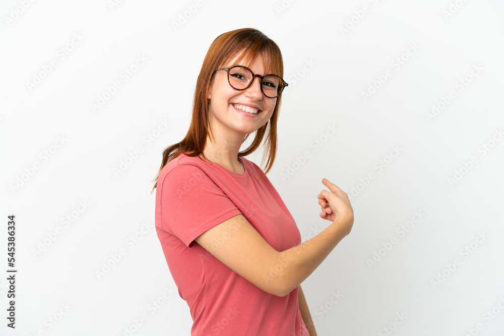 Redhead girl isolated on white background pointing back Redhead girl isolated on white background pointing back