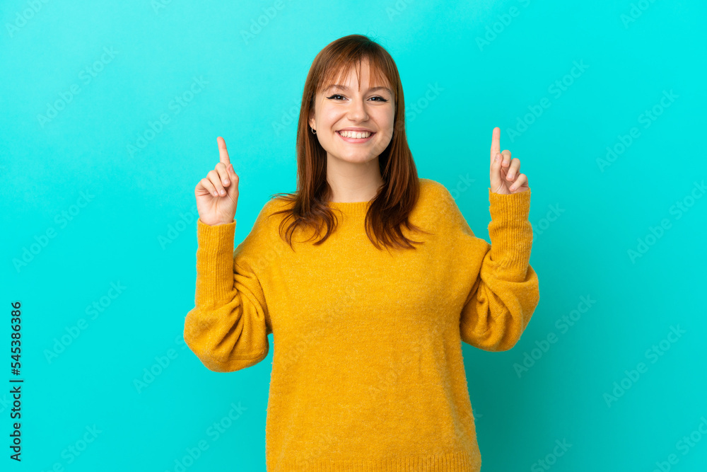 Redhead girl isolated on blue background pointing up a great idea Redhead girl isolated on blue background pointing up a great idea