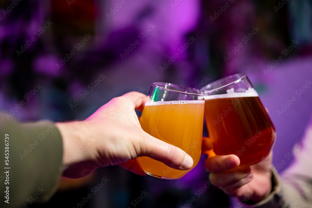 Two friends hands with glasses of craft beer at the pub or bar. taproom Two friends hands with glasses of craft beer at the pub or bar. taproom