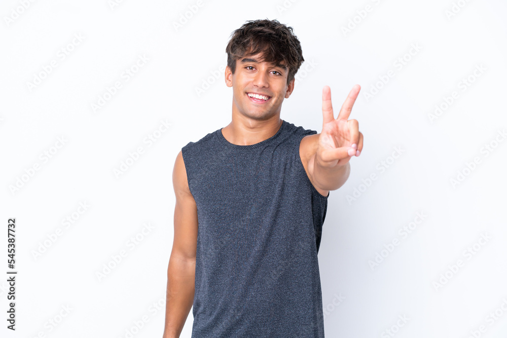 Young sport caucasian man isolated on white background smiling and showing victory sign Young sport caucasian man isolated on white background smiling and showing victory sign