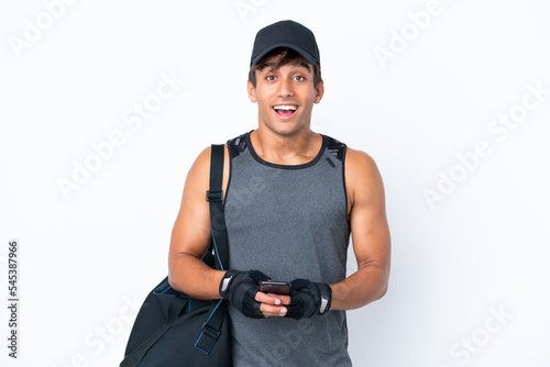 Young sport caucasian man with sport bag isolated on white background surprised and sending a message