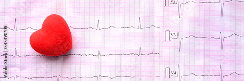 Panoramic view on red heart on sheet of pink millimeter paper with diagram of medical examination of the heart on an electrocardiogram with copy space. Medical concept and widescreen wallpaper