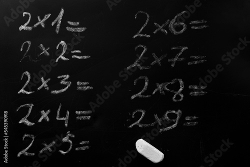 education school concept. elementary arithmetic multiplication table task written on a black chalkboard requiring a solution