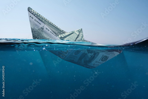 Concept paper dollar boat sinking in the sea with a view underwater. Finance and crisis, a creative idea. Falling exchange rates. Insurance photo