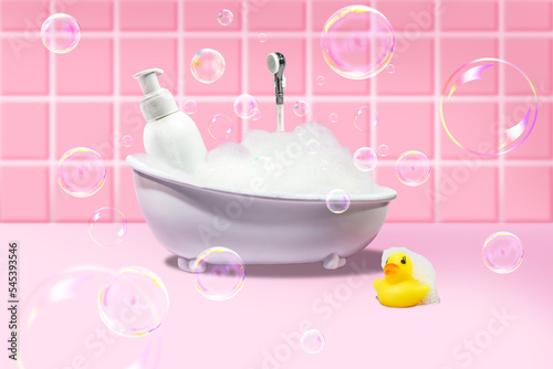 White bath with foam and soap bubbles, with a yellow duck and a bottle of cosmetic product on a pink background. Concept photo.