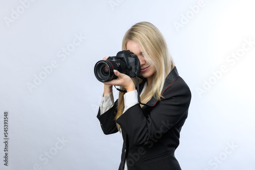 Young attractive blonde woman with modern DSLR cameras taking photo on white background