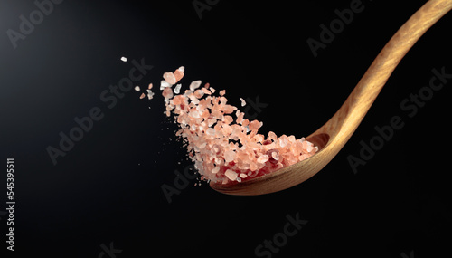 Pink Himalayan salt is poured with a wooden spoon.