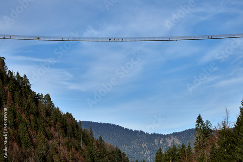 Daring tourists walking across Highline179 suspension bridge with blue sky background in Reutte, Tyrol, Austria © Thomas Marx