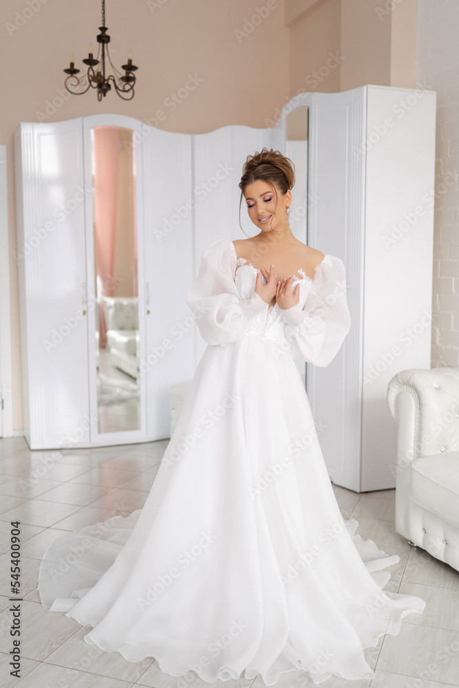 cute bride in white wedding dress posing full length in light interior cute bride in white wedding dress posing full length in light interior