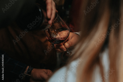 Glass of red wine held by a person at a premium wine tasting with friends and wine lovers.
