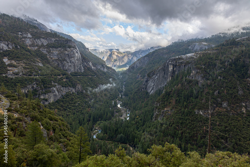 Valley in Yosemeti National Park with conifers, low clouds, cloudy sky and patches of fog, California, USA
 photo