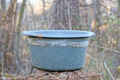 one large gray dirty old plastic basin stands on a stump in the street in nature