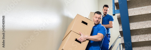 Two Movers Carrying Cardboard Boxes On Staircase photo