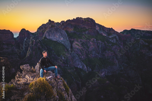 Man in leather jacket enjoying the scenic evening atmosphere of mountain terrain in the valley on Pico do Ariero. Verade do Pico Ruivo, Madeira Island, Portugal, Europe.
