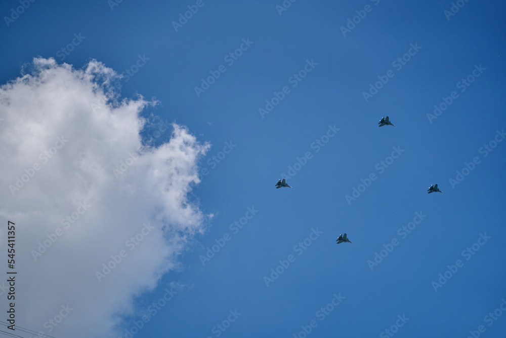 Group of Russian army air force shows aerobatics in blue sky against background of clouds. Victory parade of military aircraft over the city. Representation of aviation equipment.
