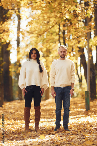 Beautiful couple standing in the autumn park at daytime