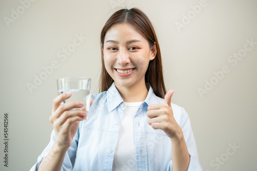 Happy beautiful, hand of asian young woman drinking, sip fresh glass of water for hydration of body, holding transparent glass in her hand, thirsty at home. Health care, healthy lifestyle concept.