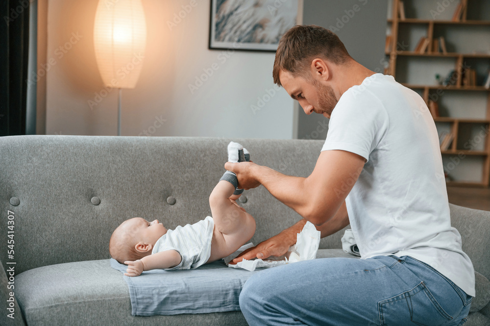 Changing diapers. Father with toddler is at home, taking care of his son Changing diapers. Father with toddler is at home, taking care of his son