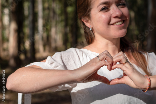 Mujer sonriente haciendo un gesto de amor juntando sus manos en forma de corazon. Enfoque selectivo en las manos photo