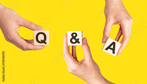 Q and A, questions concept. QnA acronym on wooden blocks in hands