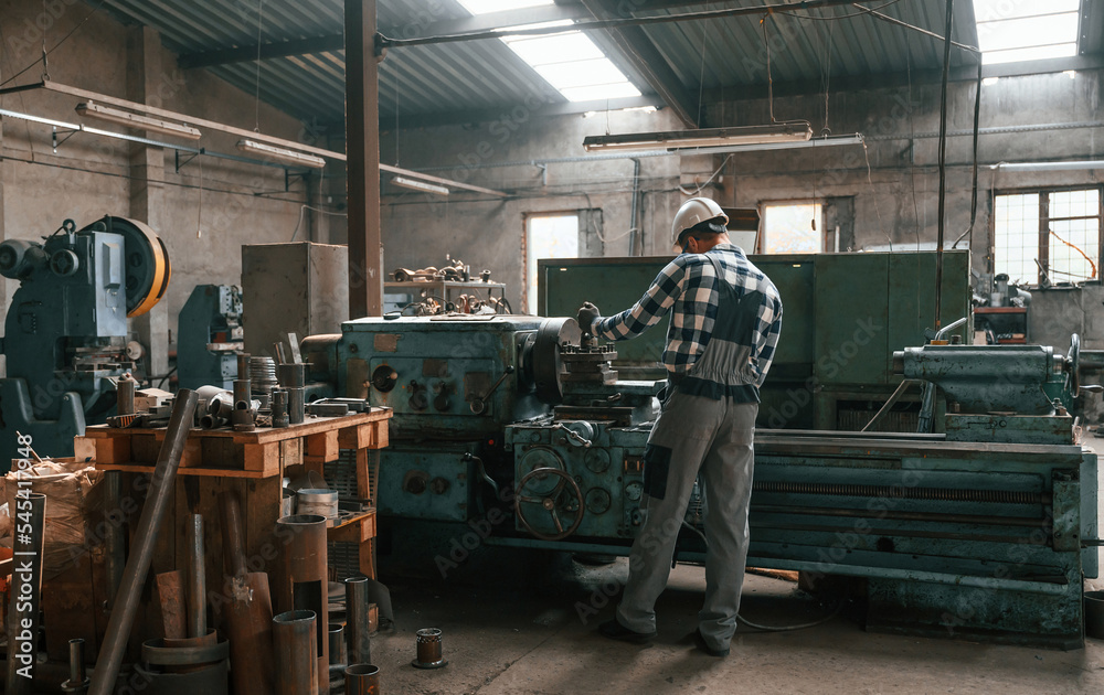 Back view. Factory male worker in uniform is indoors Back view. Factory male worker in uniform is indoors