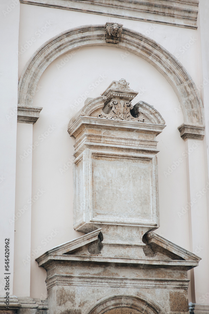 An architectural element in the form of a closed arch, a portal with seraphim and flat bas-relief columns on the corner of a Jesuit church in Lviv, Ukraine. ?opy space.