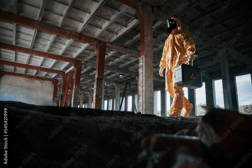 View from below. Man dressed in chemical protection suit in the ruins of the post apocalyptic building