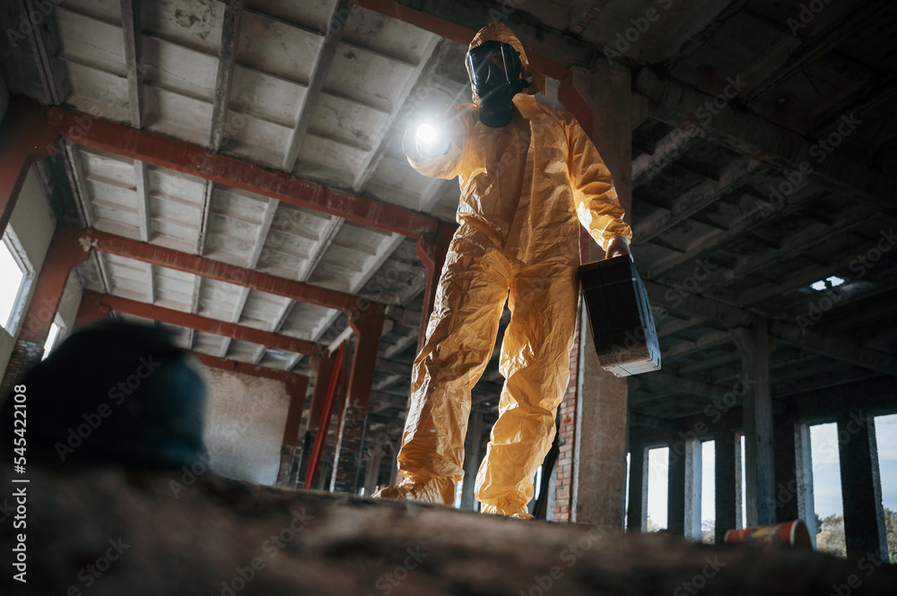 Fototapeta premium Looking below at the object. Man dressed in chemical protection suit in the ruins of the post apocalyptic building
