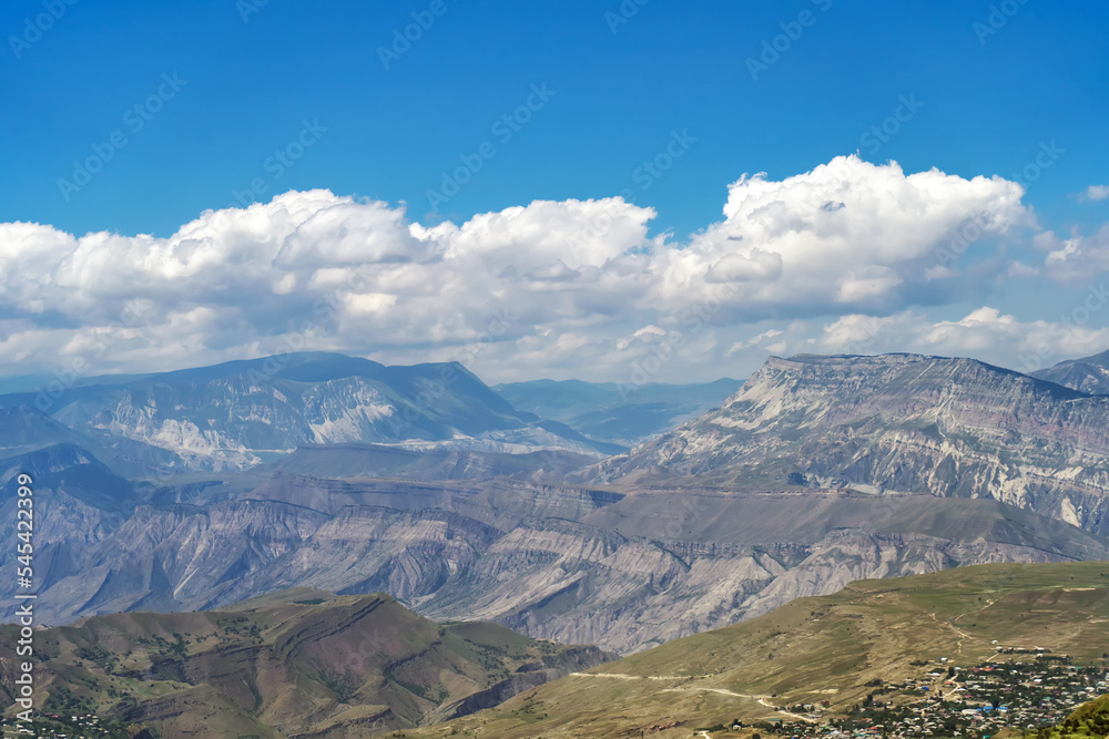 Fototapeta premium Beautiful sunny day in mountain valley and mountainous countryside landscape in summer. Mountain range under cloud blue sky. Beautiful view on mountains valley between high peaks.