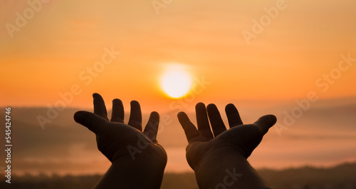 Faith of christian concept: Spiritual prayer hands over sunshine with blurred beautiful sunrise or sunset background. Christians who have believe, faith in God morning prayer.