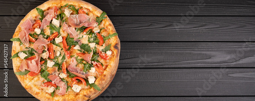 Pizza Prosciutto on a dark wooden background, top view. Banner