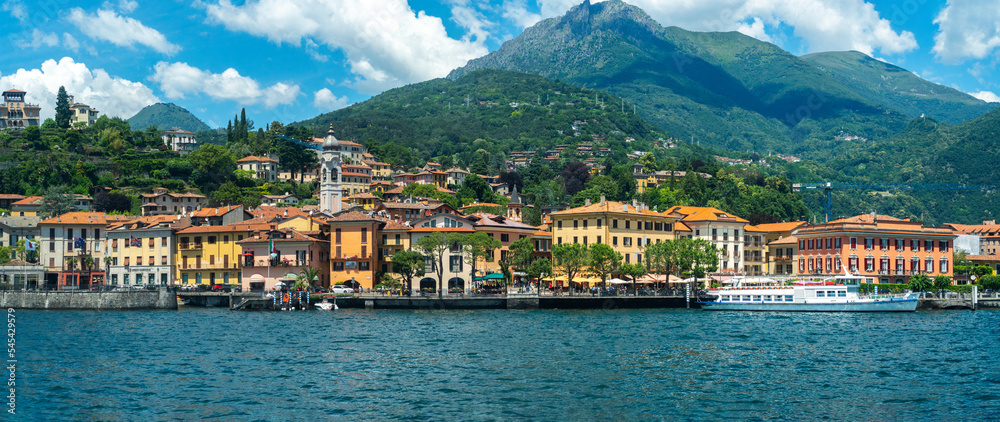 Beautiful wide panorama of Menaggio, a picturesque town of ancient origins overlooking Lake Como, with green Alps in the background on a sunny summer day. June, 2018. Lombardy, northern Italy.