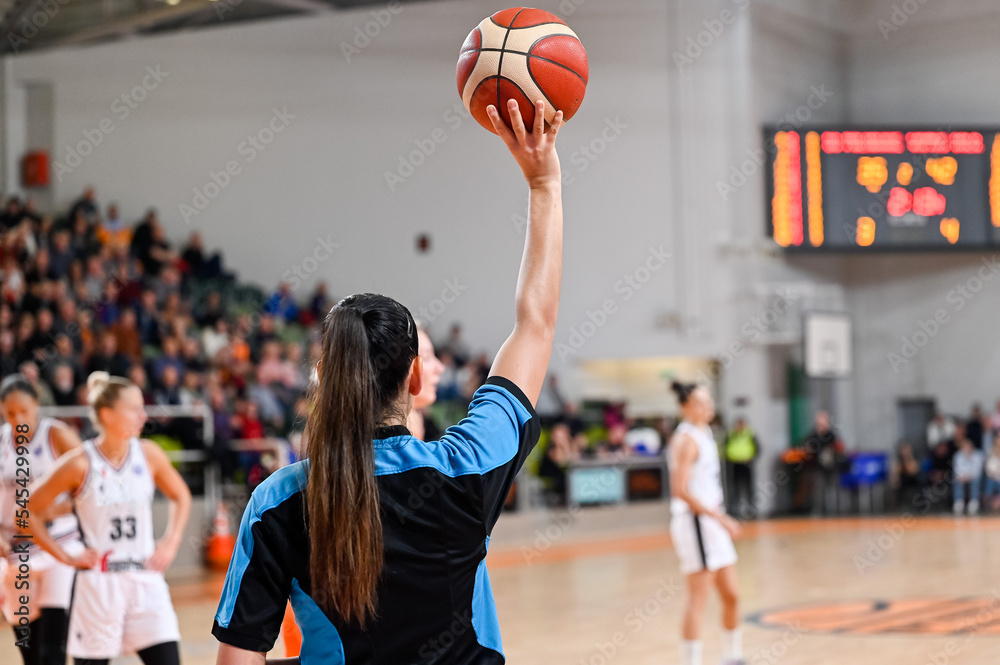 Woman referee keeps the ball during basketball match.