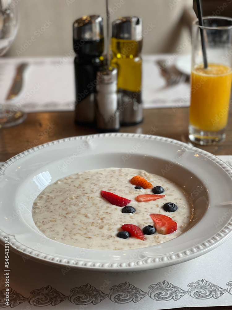 Plate of oatmeal with strawberries and blueberries and a glass of fresh juice Plate of oatmeal with strawberries and blueberries and a glass of fresh juice