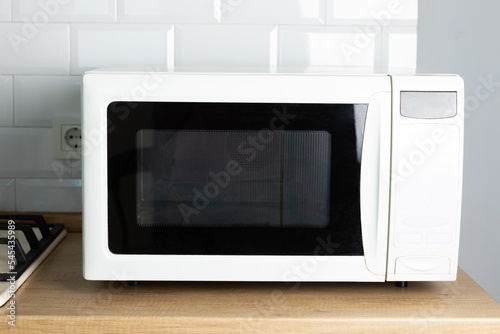 Modern white microwave on the kitchen countertop.Using microwave everyday in the kitchen. The concept of cooking.