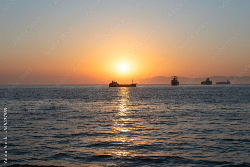 Beautiful orange sunset over the sea with a silhouettes of ships and soft selective focus. Beauty of nature concept Beautiful orange sunset over the sea with a silhouettes of ships and soft selective focus. Beauty of nature concept