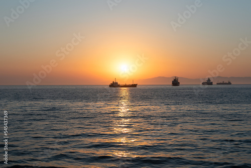 Beautiful orange sunset over the sea with a silhouettes of ships and soft selective focus. Beauty of nature concept © Rina Mskaya