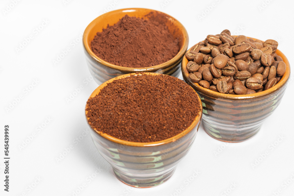 Cups with roasted coffee beans and ground coffee, white background and copy space. Cups with roasted coffee beans and ground coffee, white background and copy space.