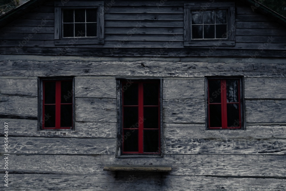 Closeup of an abandoned house with red windows Closeup of an abandoned house with red windows
