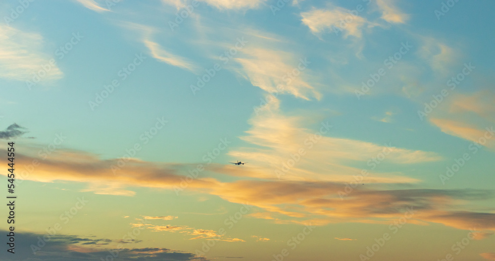 Jet airplane take off in sunset. Dark silhouette of a plane is gaining altitude.  Against a background of yellow sky