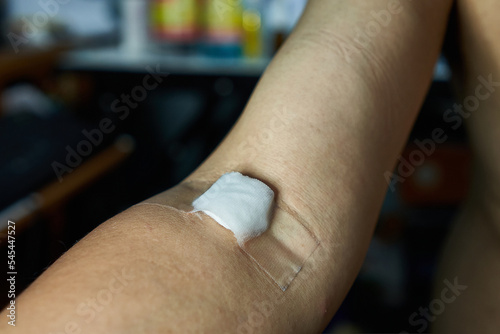 Patient arm has cotton swab to close the wound after blood test or Intravenous drip iv drip treatment.                    