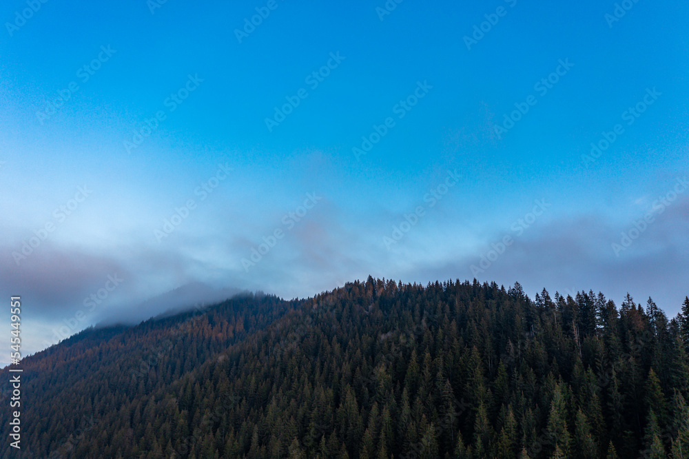 Mountain atmospheric landscape of high mountains in thick fog in rainy weather, panorama of mountain tops in thick clouds.