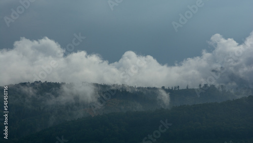 Fototapeta Naklejka Na Ścianę i Meble -  góry porośnięte lasem, mgła i niskie białe chmury, ciemne niebo