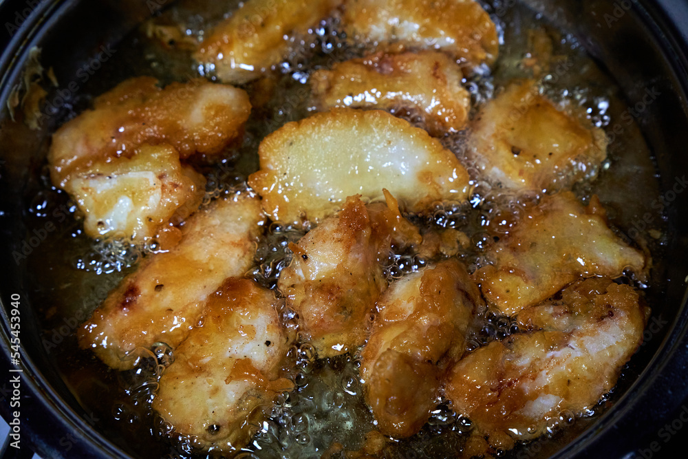 Pieces of fish are fried in boiling oil. Cooking fish in batter. Pieces of fish are fried in boiling oil. Cooking fish in batter.