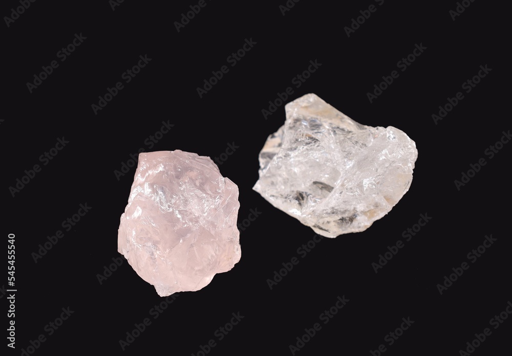 Uncut clear and pink quartz gemstones on black background.