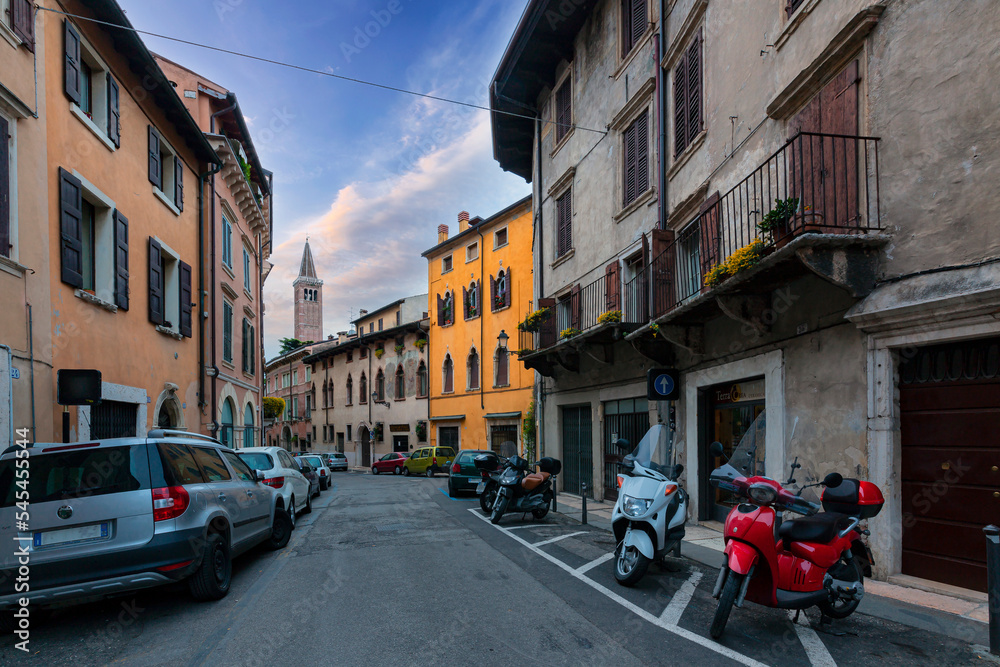View of narrow street at historic centre of Verona, Italy. Facades of houses in morning sun. 