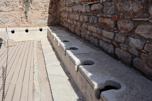 Fotografie Ancient public Toilet bathroom seats on Ephesus made of rocks, bricks, granite a