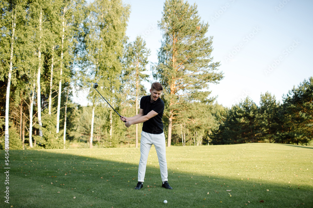 Male athlete plays golf on the field. Strong hit on the ball. High quality photo