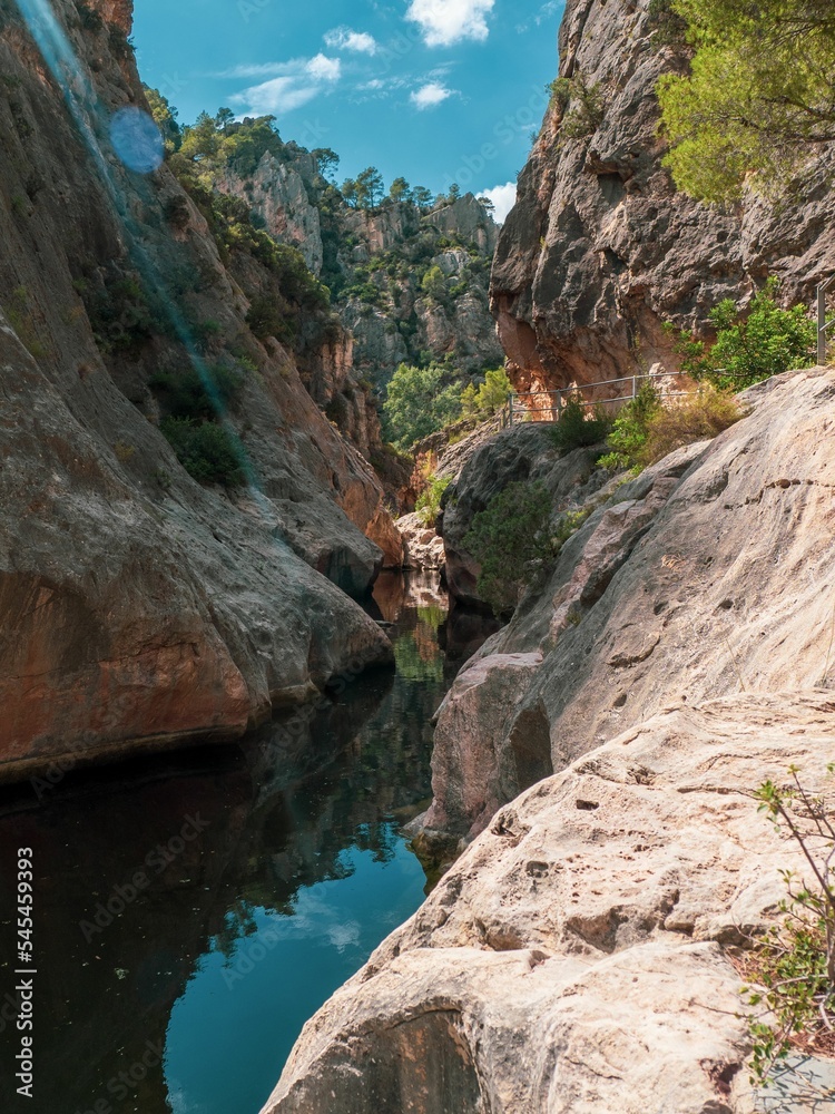 Vertical shot of water stream between rocky mounts in the sanctuary of La Fontcalda, Spain